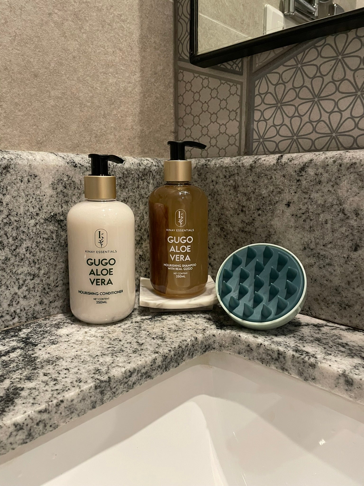 Two bottles of kinay essentials  Gugo Aloe Vera products on a bathroom counter with a textured wall and mirror in the background.