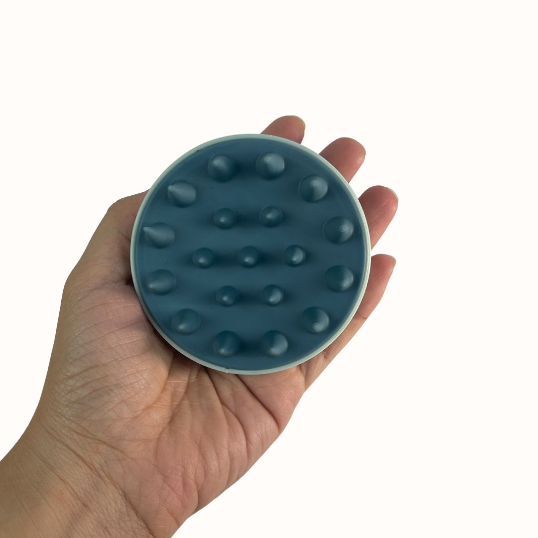 Hand holding a blue textured round object against a white background