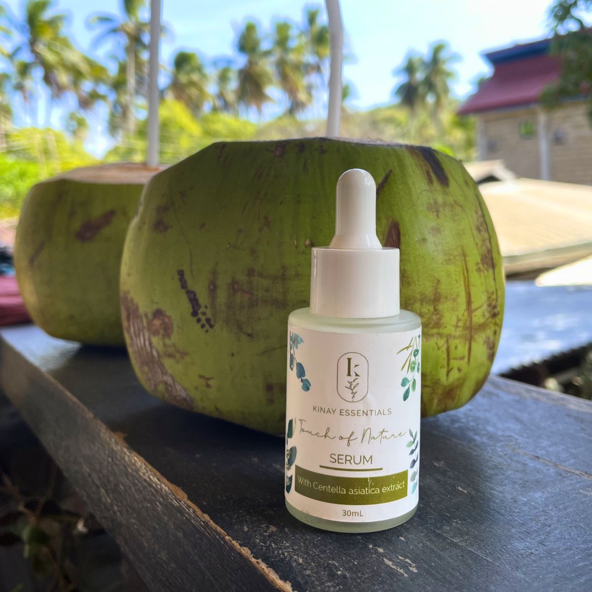 touch of nature face serum on a wooden surface with coconuts in the background.